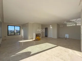 Ambiente interno de uma sala ampla com piso claro e grande janela.