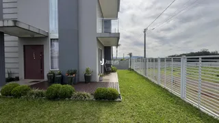 Fachada de um imóvel residencial com jardim e cerca de madeira.