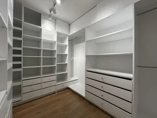 Ambiente interno com estantes e armários brancos em um imóvel.