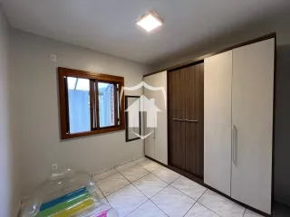 A foto mostra o interior de um quarto com paredes claras e piso de cerâmica.