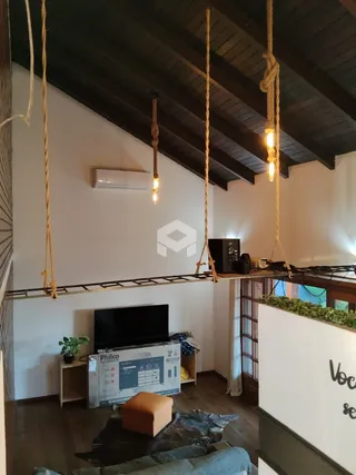 Sala de estar com teto de madeira aparente e televisão na parede.