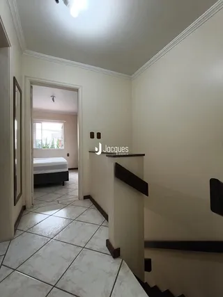 Hall de entrada com piso de cerâmica e parede branca em uma residência.