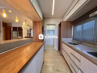 Vista interna de uma cozinha com armários de madeira clara e bancadas.
