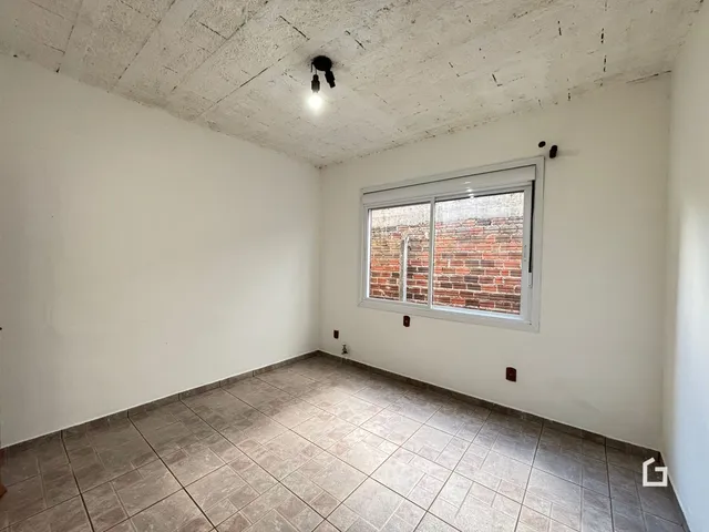 Foto de um cômodo interno com piso de cerâmica e teto de concreto aparente.