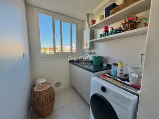 Vista interna de uma cozinha com armários brancos e janela em Lajeado.
