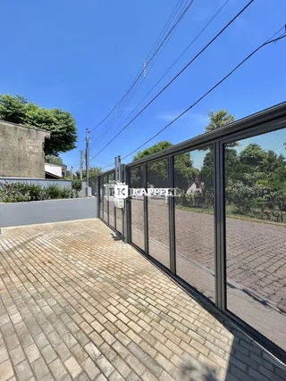 Área externa pavimentada com tijolos e cerca de metal.