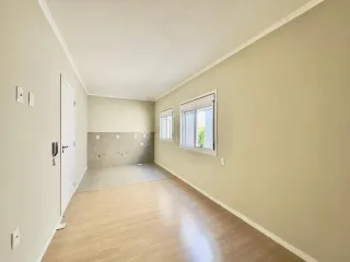 Hall de corredor com piso de madeira clara e paredes em tom bege.