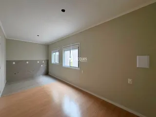 Interior de uma sala com piso de madeira e parede de concreto aparente.
