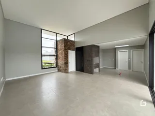 Uma ampla área comum com piso claro e paredes cinzas.