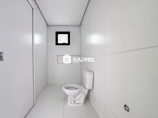 Banheiro com paredes e piso brancos e vaso sanitário visível.