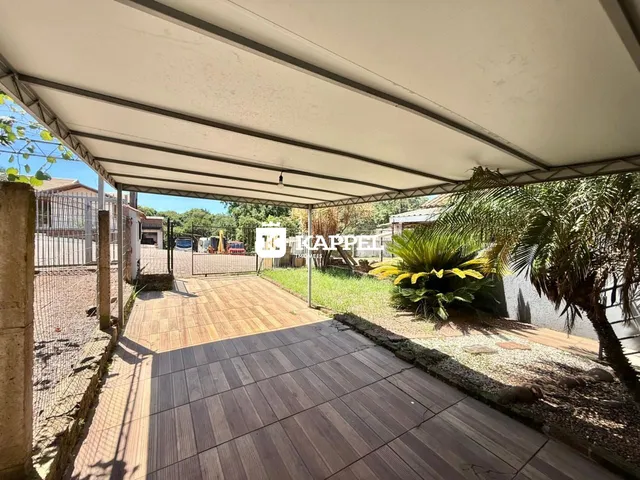 Pátio externo com deck de madeira coberto por uma estrutura de pergolado em Lajeado.