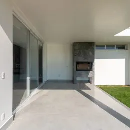 Hall de entrada com piso claro e divisória de vidro.