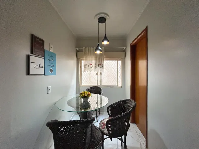 Uma sala de jantar com mesa de vidro e cadeiras de vime.
