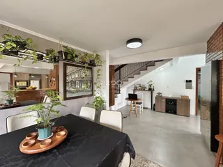 Ambiente interno de uma sala de estar com pé direito alto e decoração rústica.