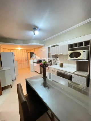 Cozinha com armários brancos e bancada clara em ambiente interno.