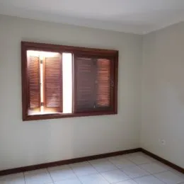 Foto interna de um cômodo com janela e piso de cerâmica.