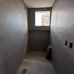 Corredor interno com paredes cinzas e janela no final.