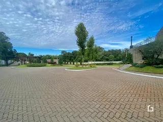 Vista externa da propriedade com área pavimentada e jardim.