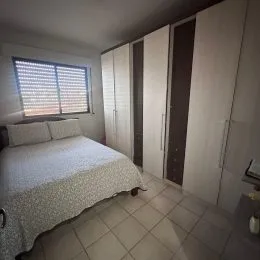 Quarto com cama e armários brancos em um imóvel.