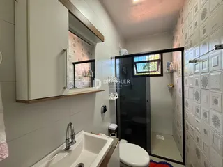 Banheiro com revestimento de azulejo branco e box de vidro