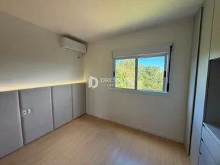 Quarto interno com piso de madeira e janela com vista para a natureza.