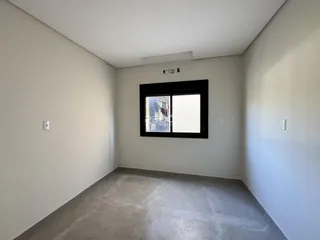 Foto de um cômodo interno com paredes brancas e piso de concreto.