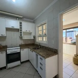 Foto de uma cozinha com armários brancos e bancadas de granito.