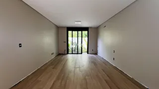 Corredor interno de uma residência com piso de madeira clara e paredes brancas.
