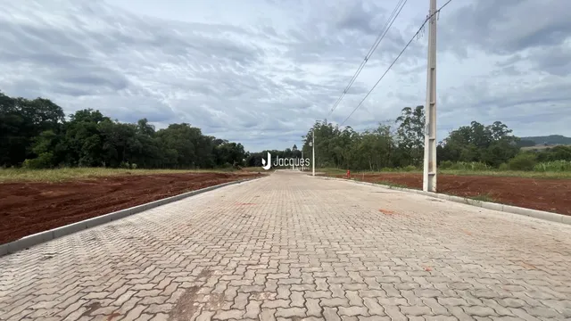 A foto mostra a entrada de uma propriedade com uma estrada pavimentada.