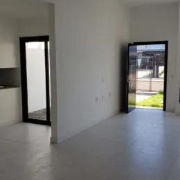 Vista interna de um corredor com paredes brancas e piso claro.