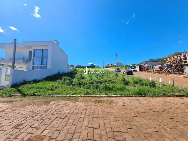 Fachada de uma residência branca em Lajeado, Brasil, com gramado e área de terra no primeiro plano.