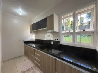 Vista da cozinha com armários de madeira e bancada escura.