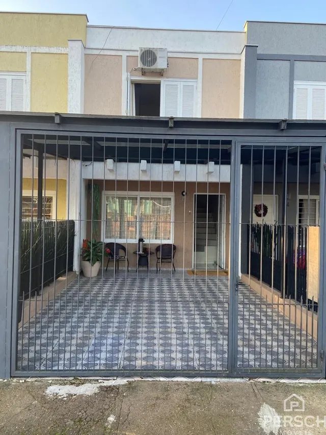 Vista externa da fachada de um imóvel com portão de metal e piso de cerâmica.
