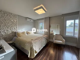 Quarto com cama grande, piso de madeira e iluminação moderna.