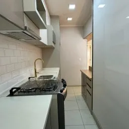 Foto de uma área de cozinha com armários brancos e bancada.