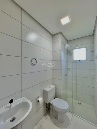 Banheiro moderno com revestimento cerâmico branco.