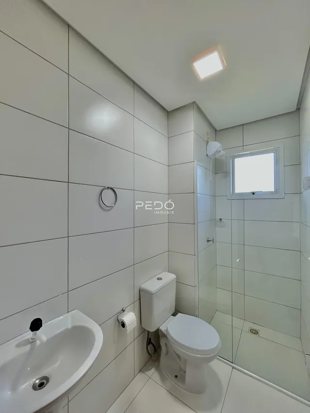 Banheiro moderno com revestimento cerâmico branco.