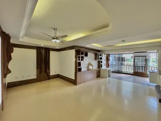 Ambiente interno de uma sala de estar com piso de madeira clara e vista para a varanda.