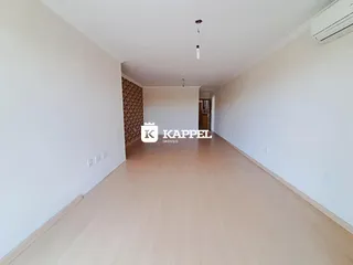 Corredor interno de um imóvel com paredes brancas e piso de madeira clara.