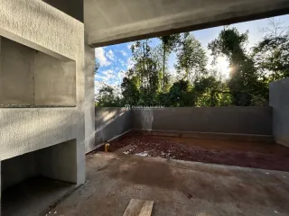 Vista externa de uma área de concreto com vegetação densa ao fundo.