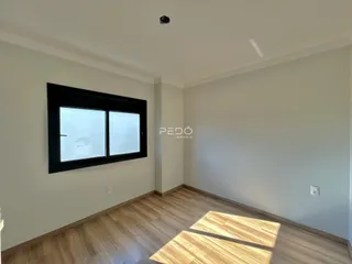 Ambiente interno de uma sala com piso de madeira e janela.