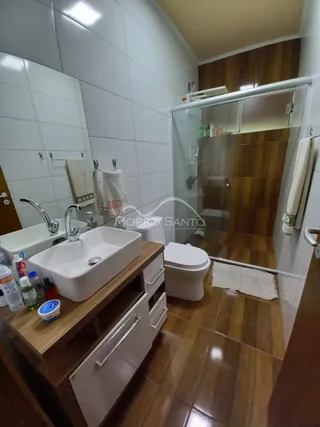 Foto de um banheiro com pia branca e box de vidro transparente.