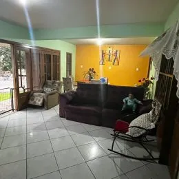 Uma sala de estar com sofá escuro e piso de cerâmica clara.