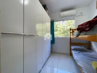 Quarto com armários brancos e cama de madeira em um imóvel no Brasil.