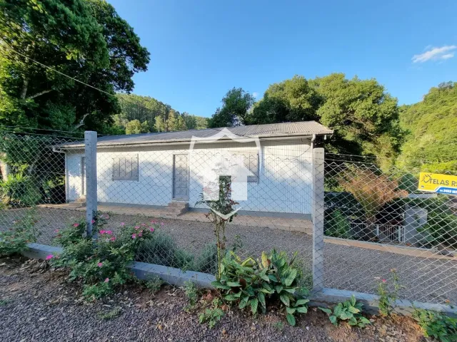 Fachada de uma casa simples em Lajeado, Brasil, cercada por vegetação.