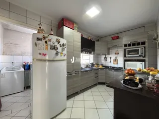 Vista interna de uma cozinha moderna com armários brancos e piso claro.