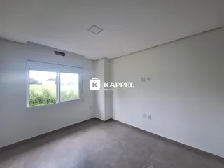 Uma sala de estar ampla com paredes brancas e piso de concreto.