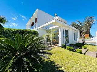 Fachada de uma casa branca moderna com jardim bem cuidado em Lajeado.