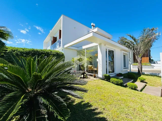 Fachada de uma casa branca moderna com jardim bem cuidado em Lajeado.