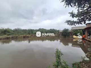 Vista externa de uma propriedade com um corpo d'água e vegetação ao fundo.